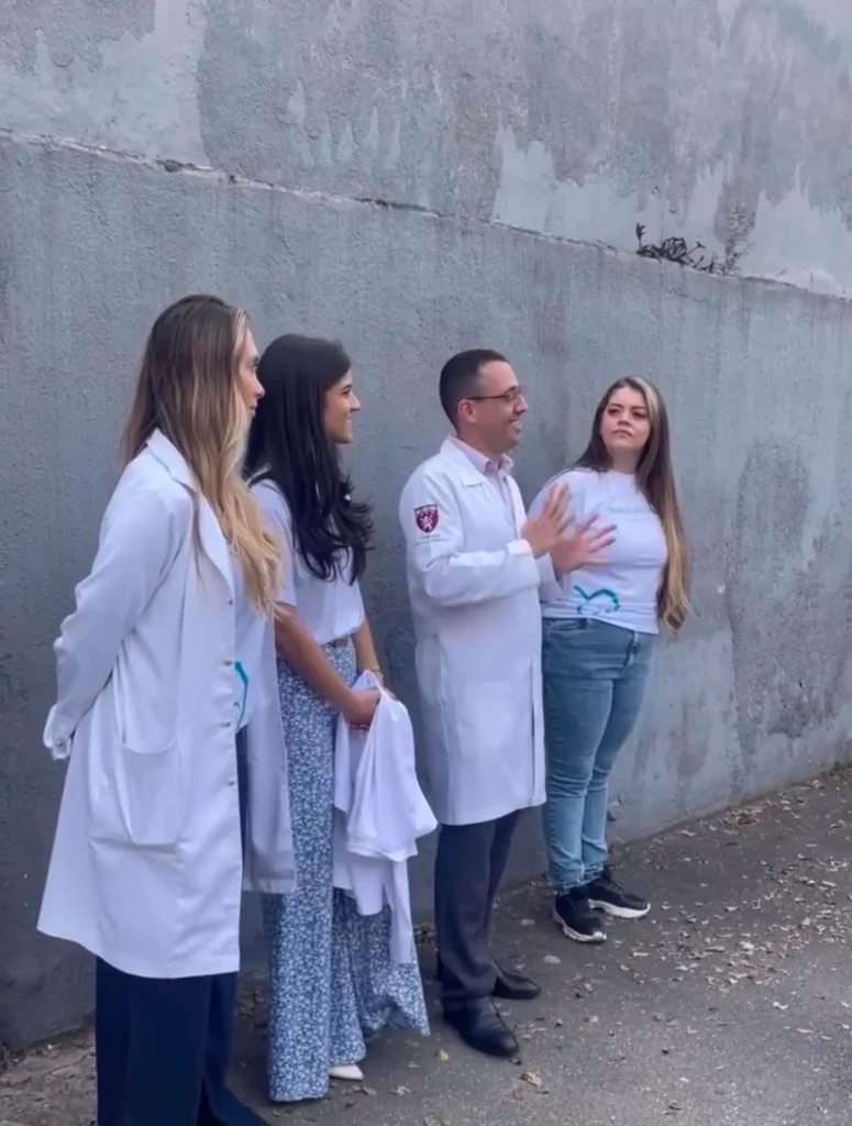 Quatro integrantes da equipe, três de jaleco branco, conversando ao ar livre.